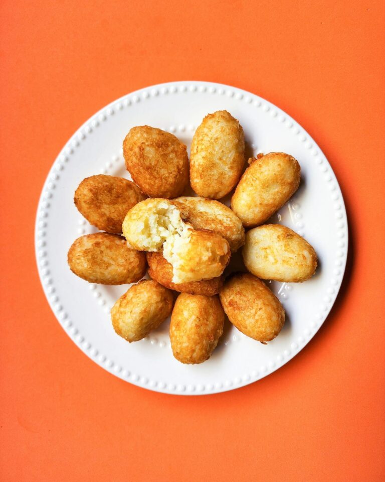 Golden fried croquettes arranged on a plate against a vibrant orange backdrop, perfect for food presentations.